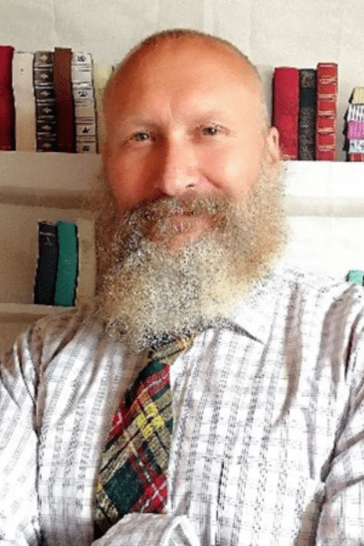 A headshot of James. He's wearing a shirt and tie, and has a long beard.