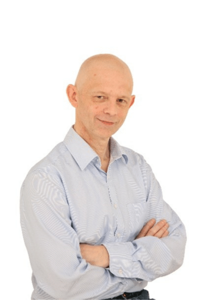 A headshot of Nick. He has his arms folded and is smiling.